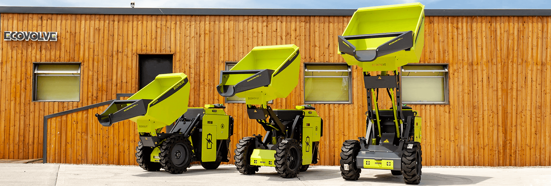 3 green electric dumpers outside building